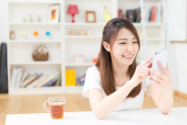 部屋でスマートフォンを見る女性